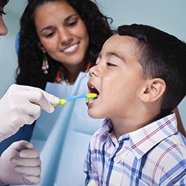 Little boy receiving tooth brushing demonstration