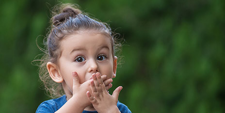 Surprised little girl covering her mouth with her hands