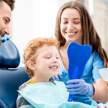 a child patient checking his smile with a mirror