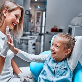 a child patient smiling and pointing at her teeth