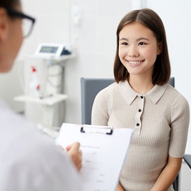 A young, female teen listening as her dentist talks to her about treatment plans