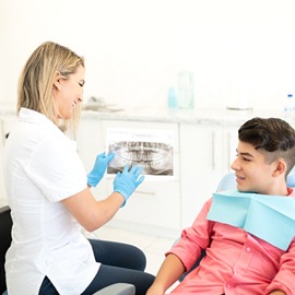 A dentist shows a teenage boy his dental X-Rays