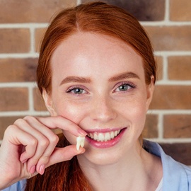 A teenage girl with red hair holding a tooth she had extracted