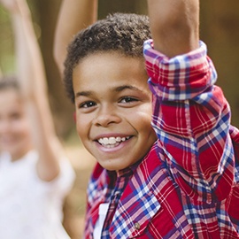 Smiling boy raising hand in class