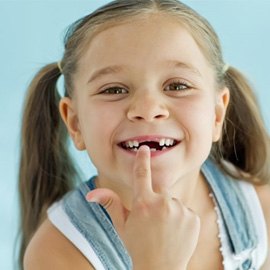 a child pointing at her teeth after tooth extractions