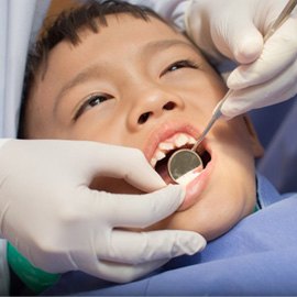 a child getting his teeth checked by his pediatric dentist