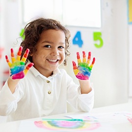 a smiling child with paint on their hands