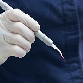 a dentist holding a soft tissue laser