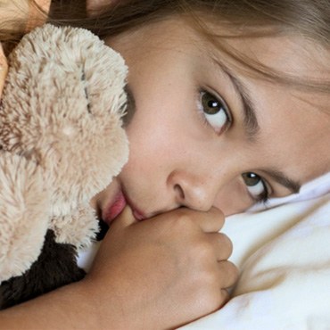 Little girl sucking her thumb while in bed 