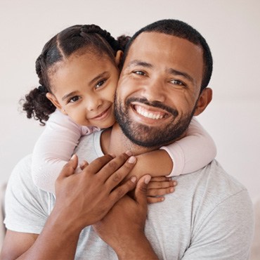 A father and daughter hugging and smiling 