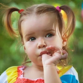 little girl with pigtails standing outside sucking thumb