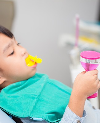A young boy sitting in a dentist chair, preparing for a dental check-up in a bright, child-friendly office.