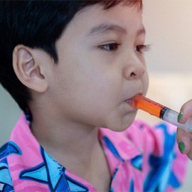 young boy taking oral medication  