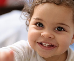 Smiling infant with a few erupted teeth