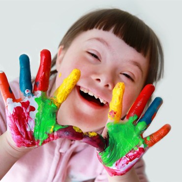 a child with different colors of paint on their hands smiling