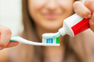 Teen putting too much toothpaste on a toothbrush 
