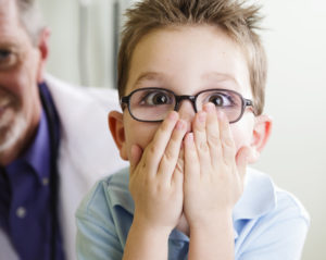 Child covering mouth with his Midland emergency dentist
