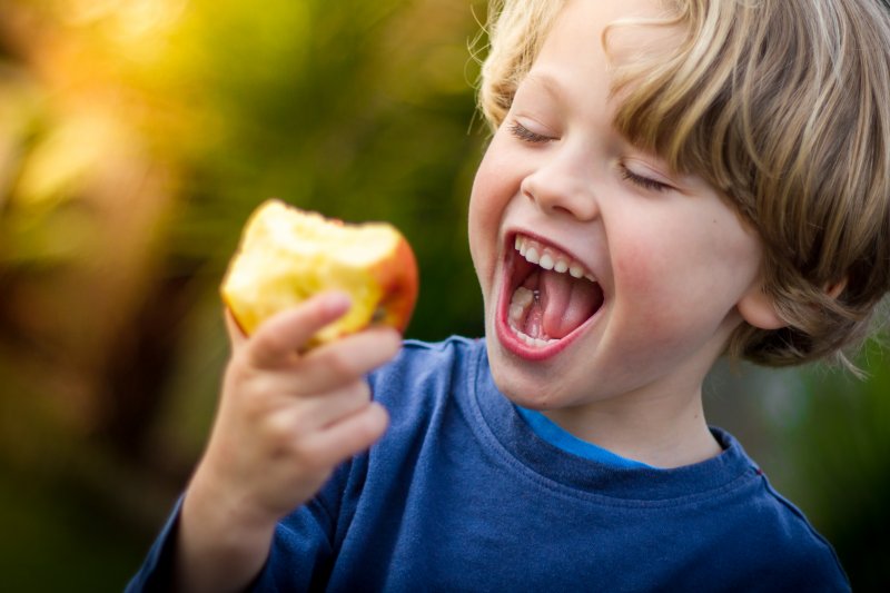 Child smiling while eating an apple