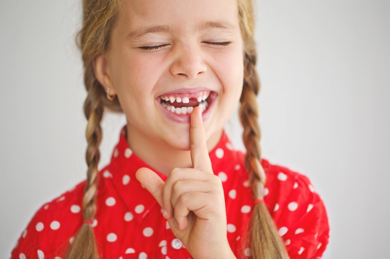 Child laughing and pointing to missing tooth