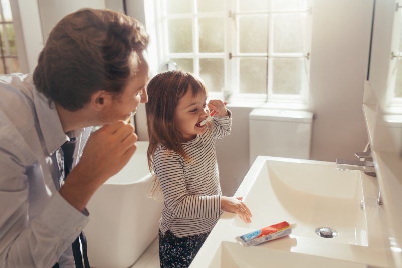 Father and daughter brushing their teeth