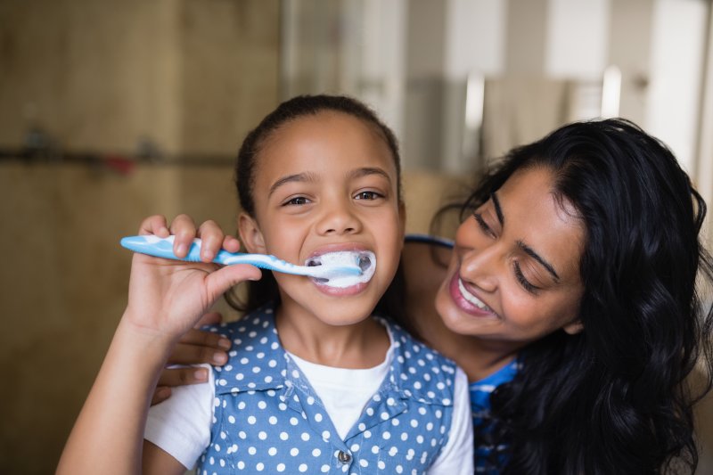 parent smiling at child brushing teeth