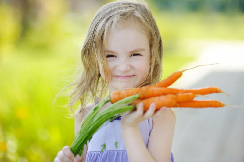girl smiling while holding carrots in Midland