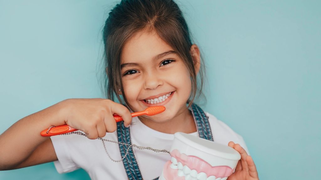 Young child pretending to brush her teeth.