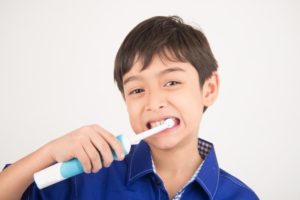 young boy using electric toothbrush