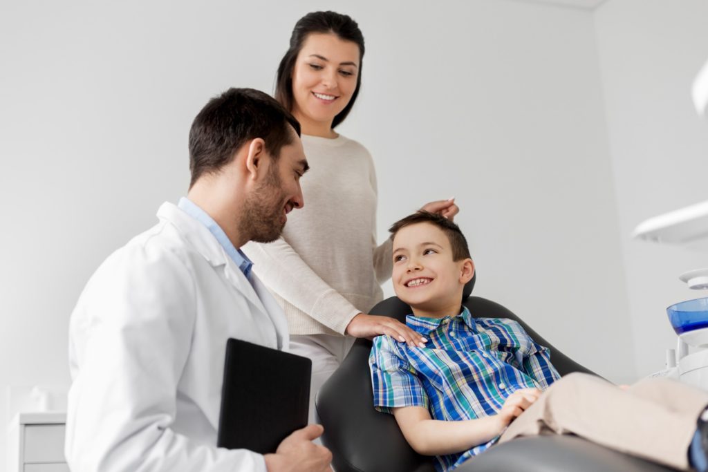 Child and parent smiling at dentist during checkup