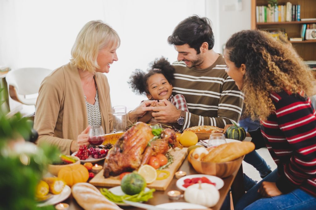 Child smiling at Thanksgiving table with family