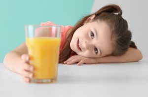a child smiling with a glass of juice in her hand