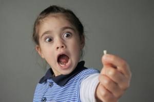 a child holding one of their baby teeth
