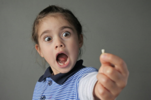 a child holding one of their baby teeth 