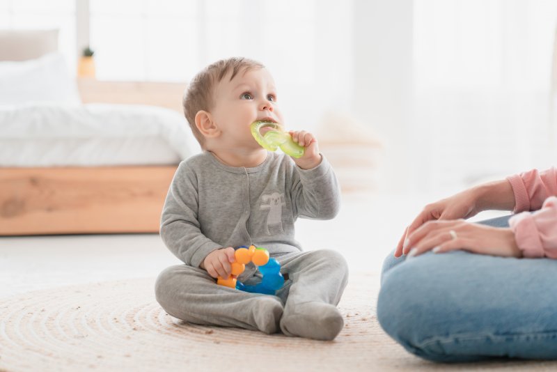 A baby teething next to their parent