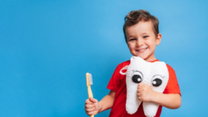 Child holding a toothbrush and tooth-shaped plush on blue background